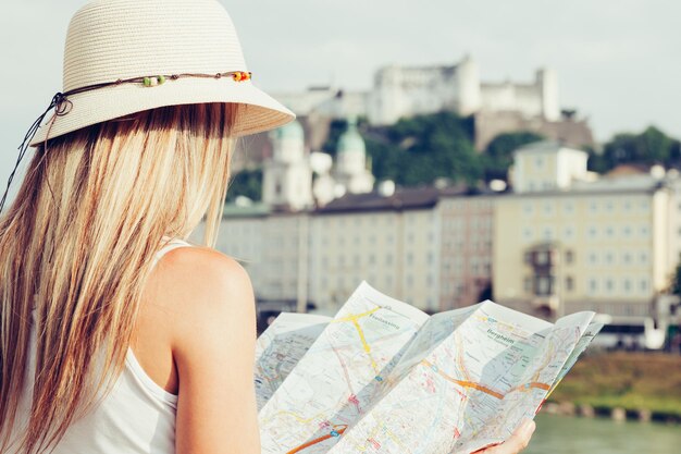 Foto turismo feminino de férias em salzburgo, áustria, segurando um mapa local