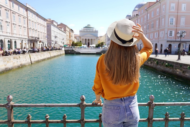 Turismo en Italia Vista posterior de una chica guapa sosteniendo un sombrero en Trieste Italia Hermosa joven visitando Europa