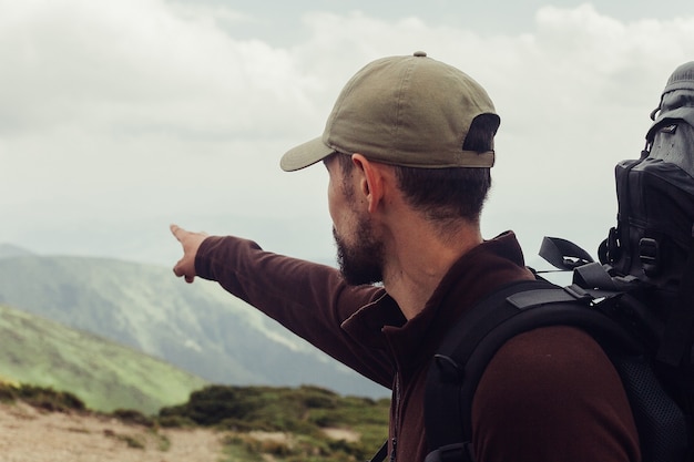 Foto turismo, montanhas, estilo de vida, natureza, conceito de pessoas - jovem de pé no topo de um penhasco nas montanhas de verão ao pôr do sol e apreciando a vista da natureza