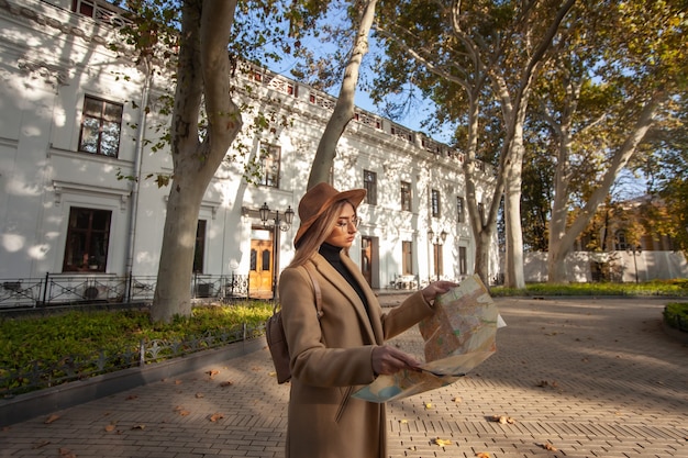 Turismo de otoño. Viajero femenino atractivo joven es guiado por el mapa de la ciudad. Hermosa chica en busca de dirección en la ciudad. Concepto de vacaciones y turismo