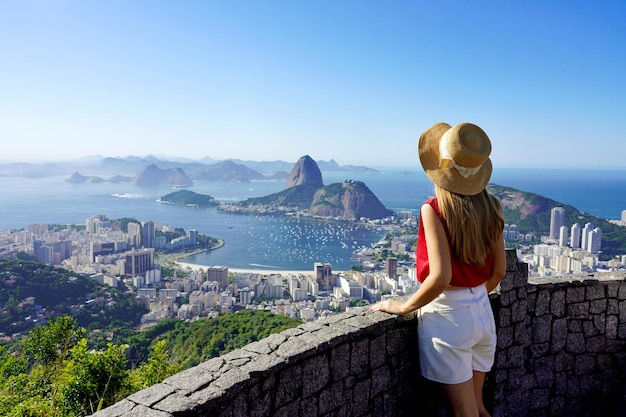 Foto turismo en río de janeiro vista trasera de una chica viajera disfrutando de la vista de la famosa bahía de guanabara con la montaña sugarloaf en rio de janeiro patrimonio de la humanidad de la unesco brasil