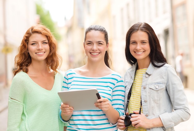 turismo, viagens, lazer, férias e conceito de amizade - adolescentes sorridentes com computador de computador de bruxa e câmera ao ar livre