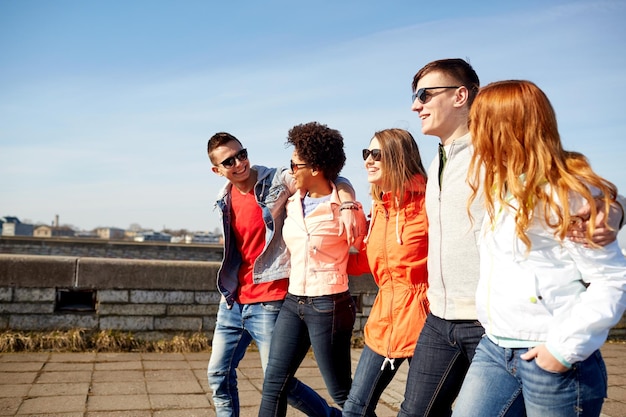 turismo, viagens, pessoas e conceito de lazer - grupo de amigos adolescentes felizes andando pela rua da cidade e conversando