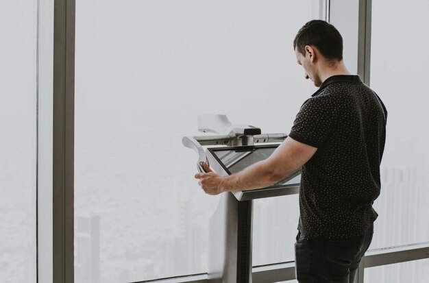 Turista adulto joven utilizando un telescopio electrónico digital del Burj Khalifa en la plataforma de observación