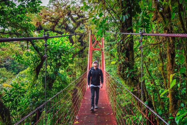 Turista andando em uma ponte suspensa na floresta de nuvens de monteverde costa rica