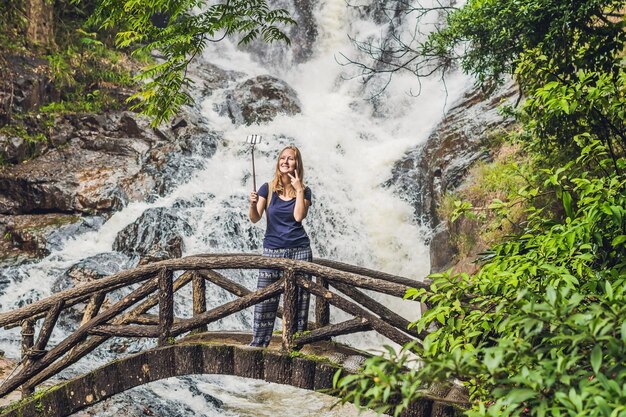 Turista animada fazendo autorretrato em frente à cachoeira