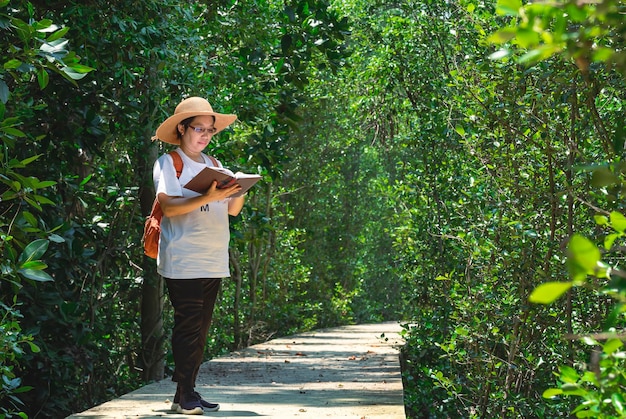 Turista asiática tomando nota en la pasarela en el bosque de manglares en el parque natural