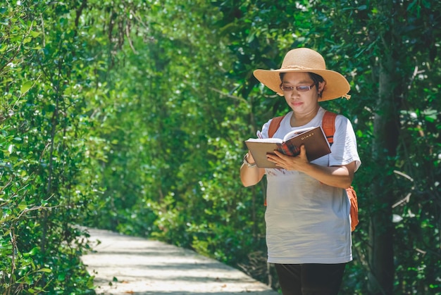 Turista asiática tomando notas durante el ecoturismo en la pasarela en el bosque de manglares en el parque natural