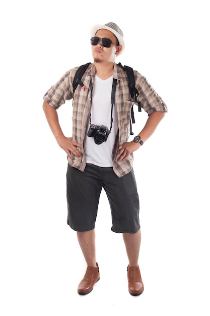 Turista asiático de mochila com chapéu, óculos de sol pretos, câmera e mochila, sorrindo com um gesto feliz