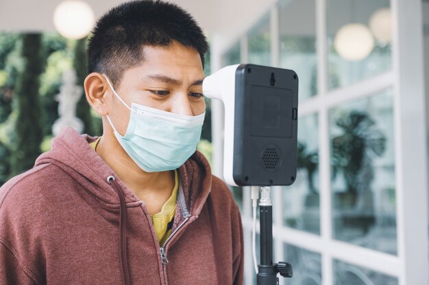 Un turista asiático ha comprobado la temperatura corporal con un detector de escáner de temperatura térmica nuevo normal