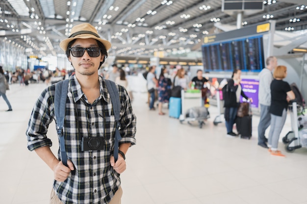 Turista asiático del paquete del bolso del hombre con la cámara en aeropuerto.