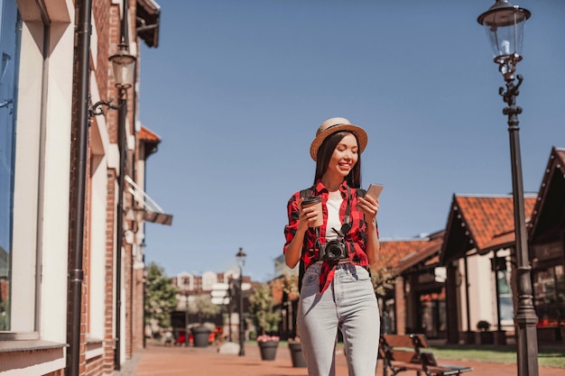 Turista asiático usando smartphone e andando na rua da cidade