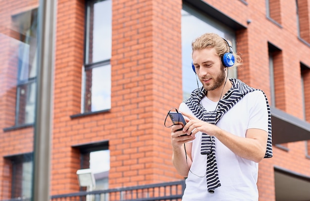 Un turista atractivo pasea por una nueva ciudad utiliza una audioguía