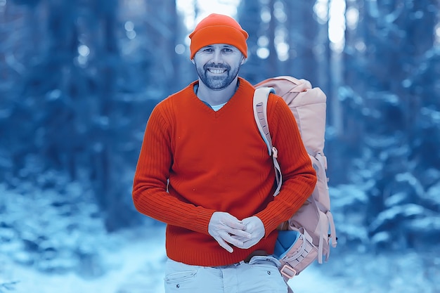 turista en el bosque invernal / el tipo viaja en el contexto de un paisaje invernal con bosque, nieve y árboles