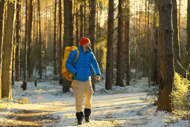 turista en el bosque invernal / el tipo viaja en el contexto de un paisaje invernal con bosque, nieve y árboles