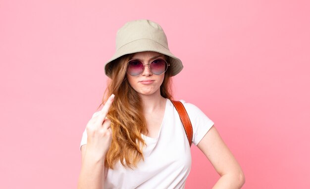 Turista de cabeza roja mujer bonita que se siente enojado, molesto, rebelde y agresivo