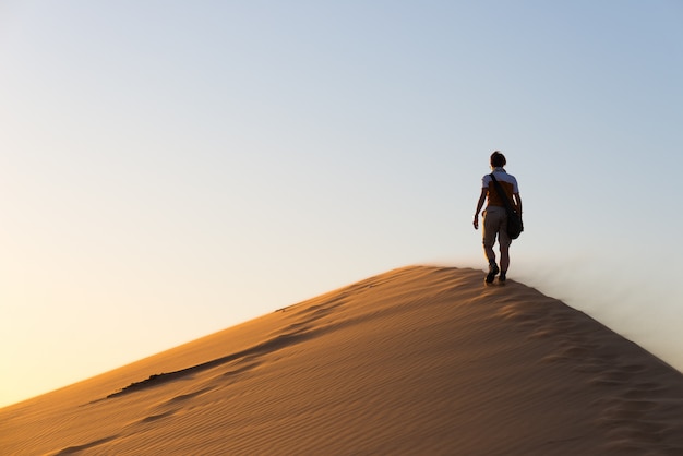 Turista caminando por las dunas de arena en Sossusvlei, desierto de Namib. Gente viajera, aventura y vacaciones en África.