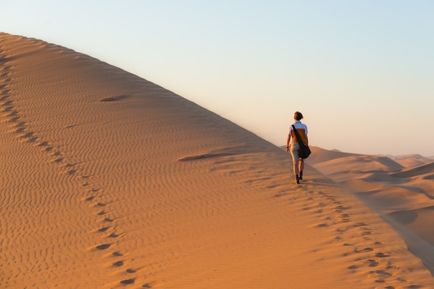 Turista caminando sobre dunas escénicas en el desierto de Namib, Namibia