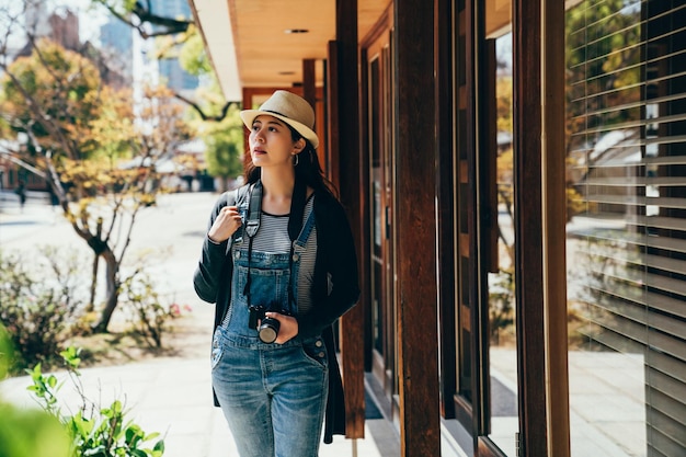 turista caminando por la ventana bajo la sombra del techo en el caluroso clima de verano. joven mochilero con cámara de viaje al aire libre en osaka, japón. gira turística en el concepto de Asia.