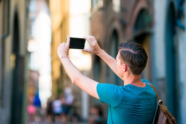 Turista caucásico con smartphone en manos caminando por las estrechas calles italianas en Roma. Joven urbano de vacaciones explorando ciudad europea