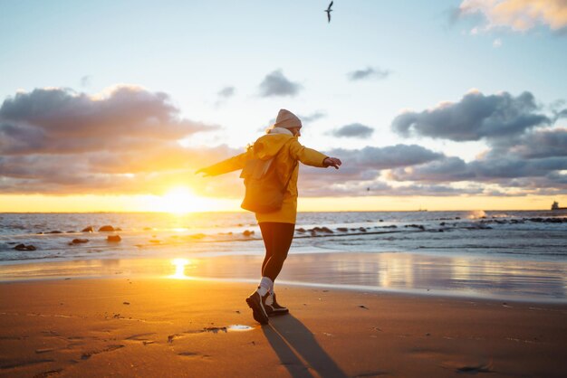 Turista con chaqueta amarilla disfrutando del paisaje marino al atardecer Estilo de vida viajes naturaleza vida activa