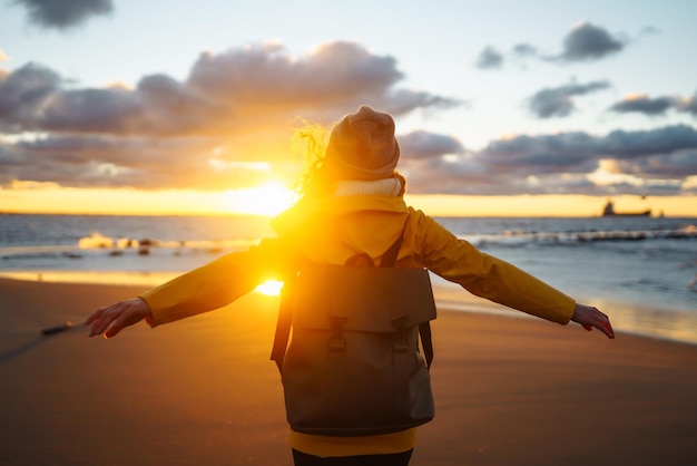 Turista con chaqueta amarilla disfrutando del paisaje marítimo al atardecer Estilo de vida viajes naturaleza vida activa