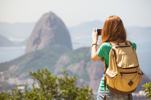 Turista chica tomando una foto en un smartphone Pao de Acucar. Rio de Janeiro.