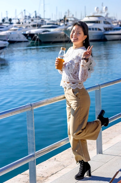 Turista chino sonriendo con dos dedos levantados en señal de victoria Mujer feliz