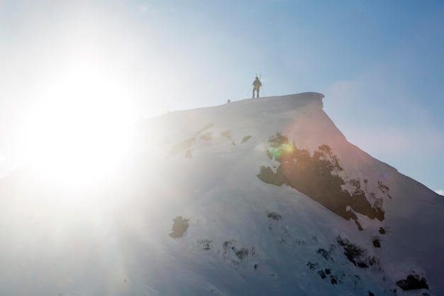 Un turista en la cima de una montaña bañada por la luz del sol