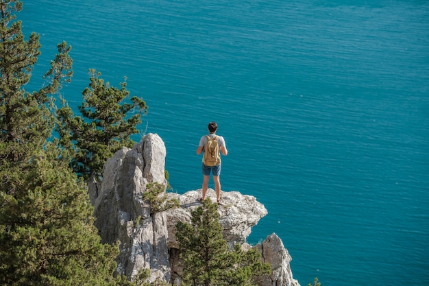 Turista com mochila desfrutar de vista para o vale do topo de uma montanha