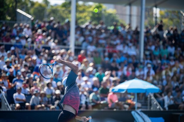 Turista com mochilas no meio de uma multidão assistindo a um evento esportivo em um estádio Fãs de esportes torcendo e assistindo tênis no Aberto da Austrália na Austrália Fãs de esporte de verão quente vestindo roupas de verão