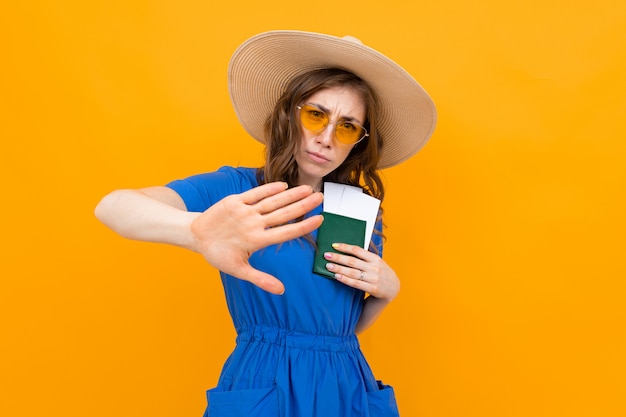Turista com um passaporte e bilhetes em suas mãos em um fundo amarelo, um gesto mostra caindo atrás dela