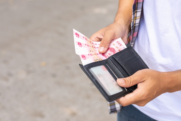 Turista contando o revisando billetes en billetera negra que encontró en la atracción turística