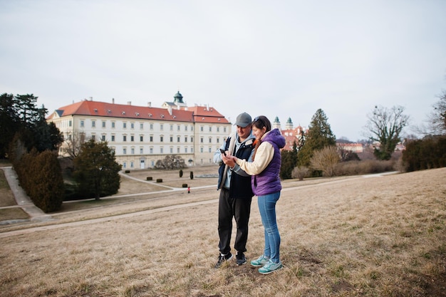 Turista de casal no palácio de Valtice olha no celular República Tcheca