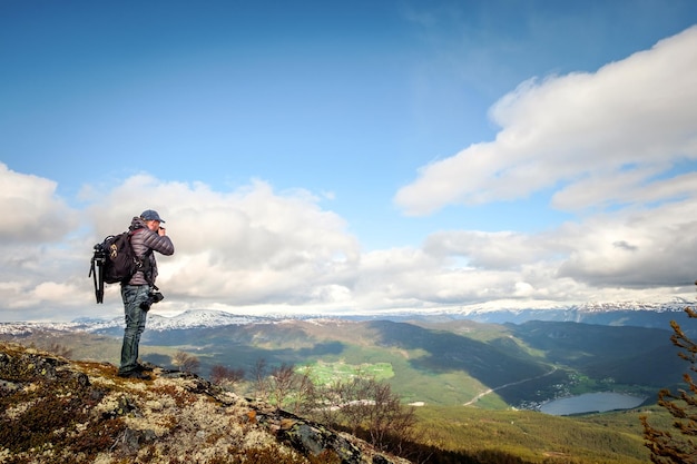 Turista de fotógrafo de natureza com câmera dispara em pé no topo da montanha. Bela Natureza Noruega.