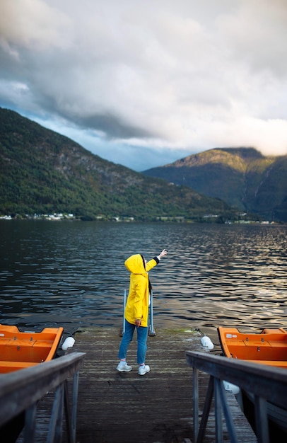 Turista de garota em uma jaqueta amarela posando no lago na Noruega Viajando aventura de estilo de vida