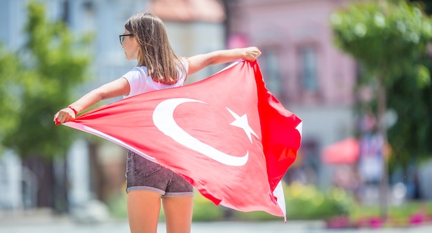 Turista de garota feliz andando na rua com a bandeira da turquia.