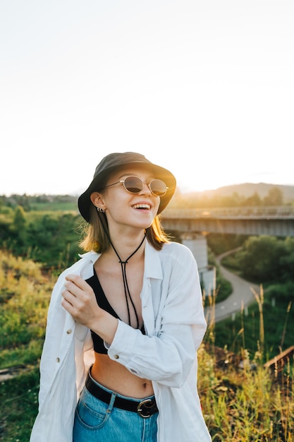 turista de garota feliz em roupas elegantes de verão fica nas montanhas no fundo da ponte