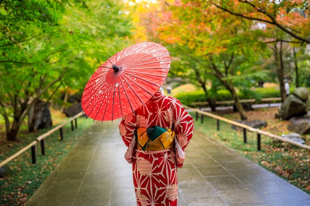 Turista de garotas vestindo quimono vermelho e guarda-chuva deu um passeio no parque na temporada de outono no Japão