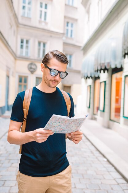 Turista de homem com um mapa da cidade e mochila nas ruas da europa.