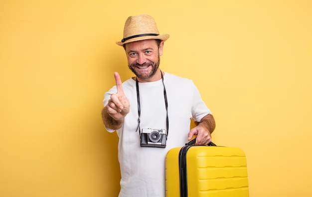 Turista de homem de meia idade sorrindo com orgulho e confiança, fazendo o conceito de viagem número um