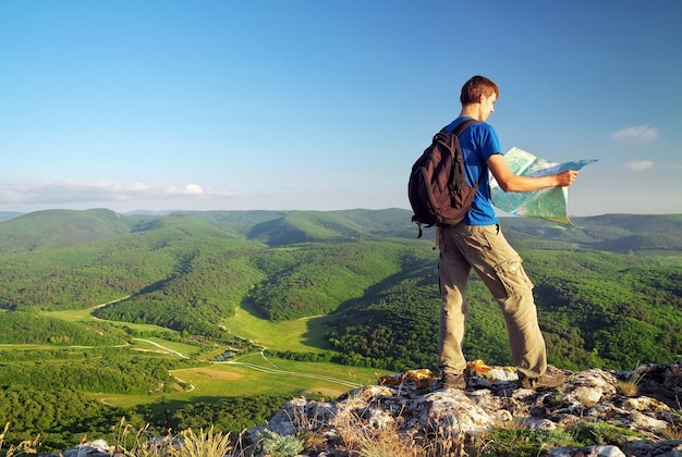 Turista de homem na montanha leu o mapa. Homem no topo da montanha. Conceito de turismo