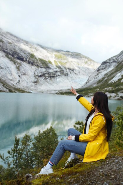 Turista de jaqueta amarela posando no lago na Noruega Mulher ativa relaxando na Noruega