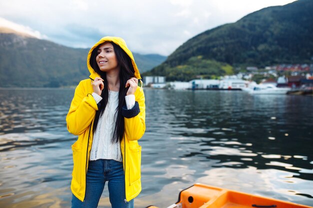 Turista de jaqueta amarela posando no lago na Noruega Mulher ativa relaxando na Noruega