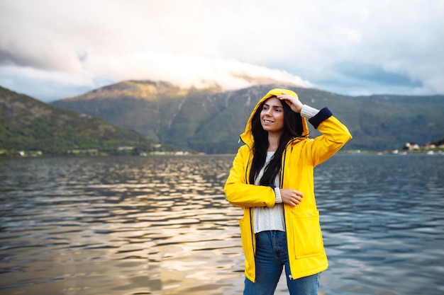 Turista de jaqueta amarela posando no lago na Noruega Mulher ativa relaxando na Noruega
