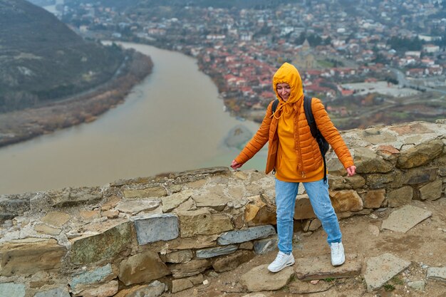 Turista de jovem regozija-se posando contra uma incrível paisagem natural. a confluência de dois rios na cidade de mtskheta, na geórgia.