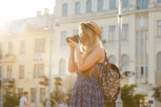 Turista de menina em um chapéu com um mapa viaja através de uma cidade desconhecida.