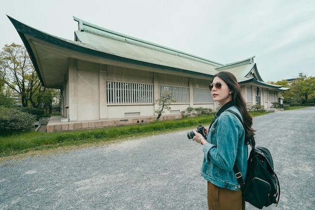 Turista de mulher asiática usando câmera profissional