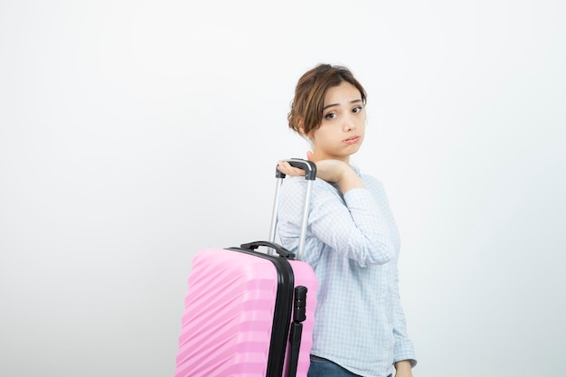 Turista de mulher em pé e segurando a mala de viagem rosa. Foto de alta qualidade