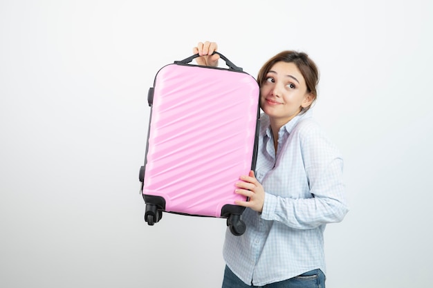 Foto turista de mulher em pé e segurando a mala de viagem rosa. foto de alta qualidade